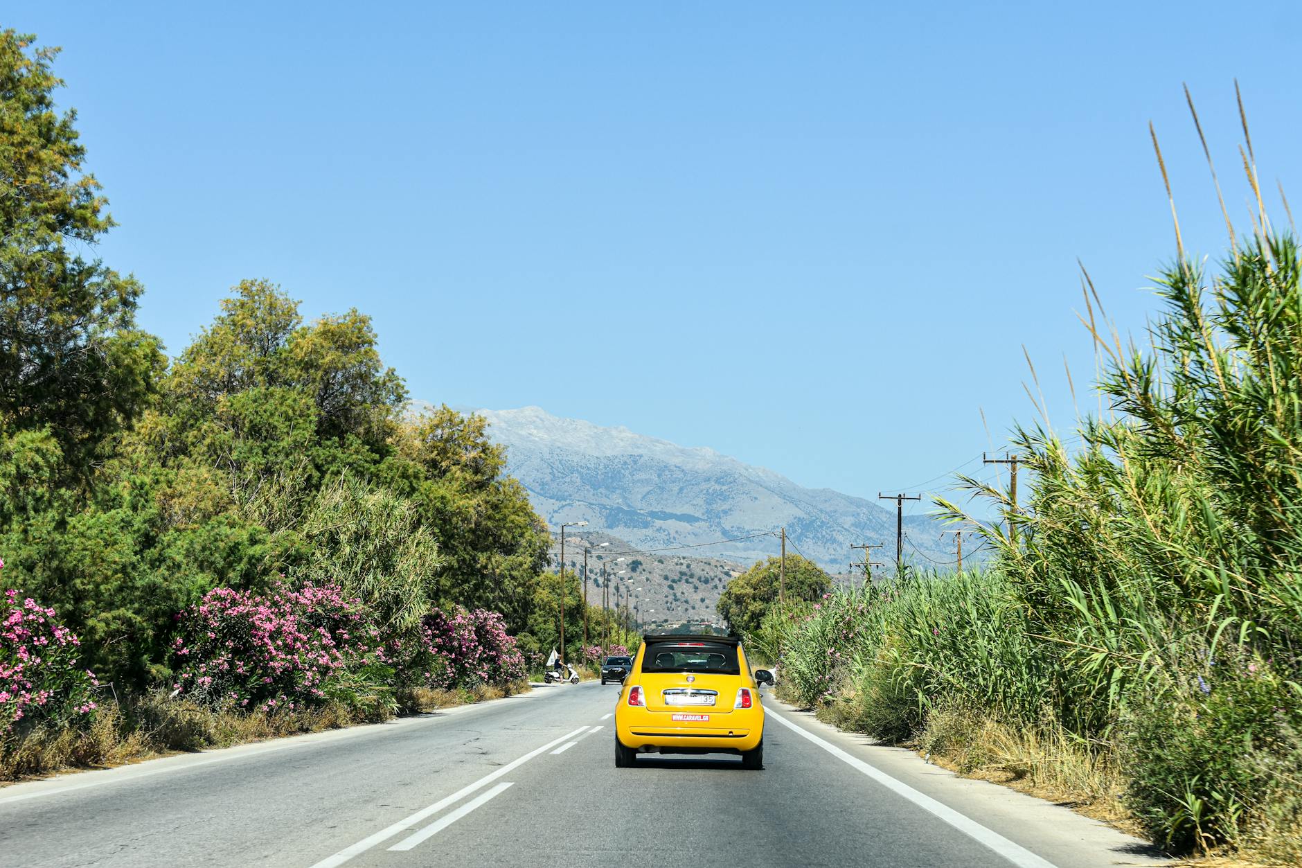Car rental driving along a scenic Greek road with Mediterranean landscape views