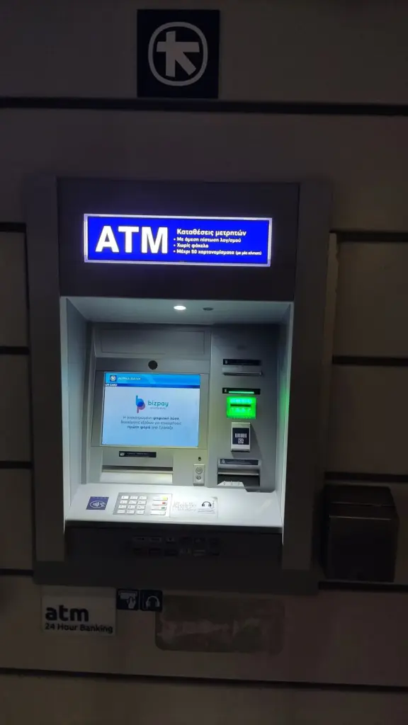 Alpha Bank cash machine beneath the bank's logo, the kind of ATM to use when weighing cash or card in Greece