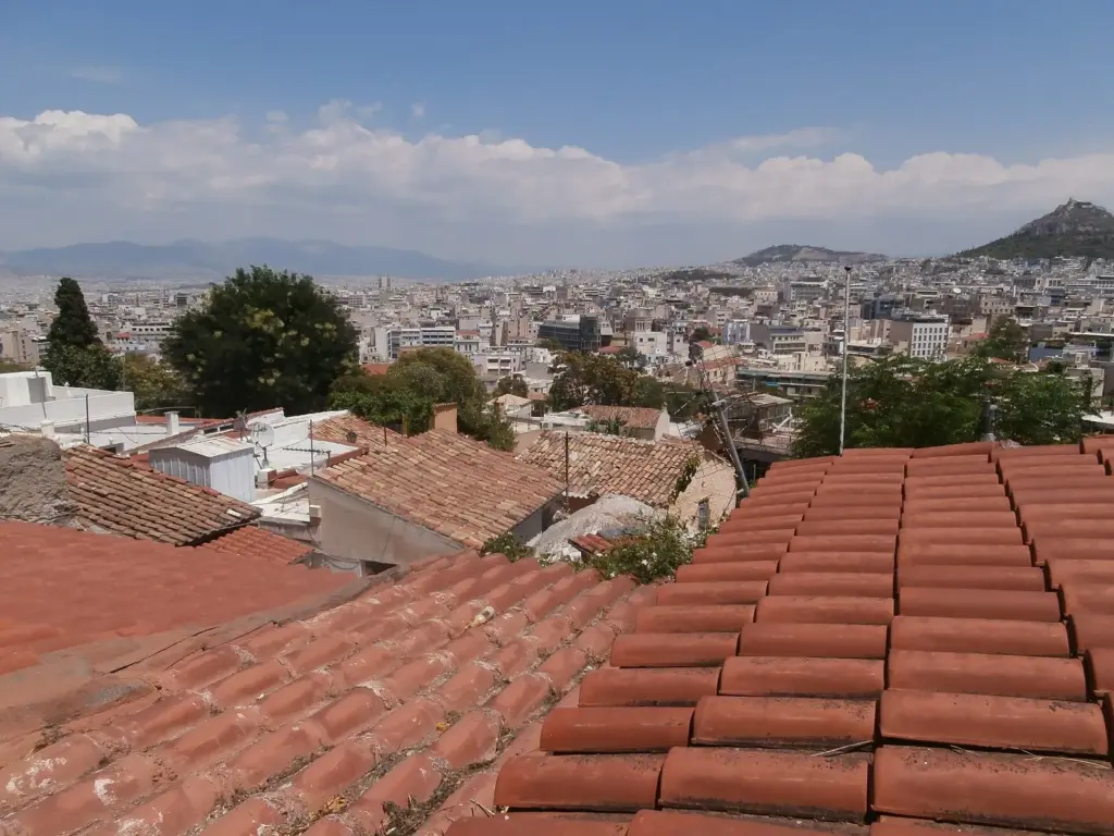 Terracotta roofs of Anafiotika with central Athens and Lycabettus Hill beyond