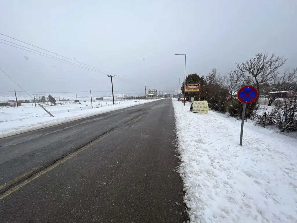 A cleared road with snow banked along both verges leading out of Arachova towards Eptalofos