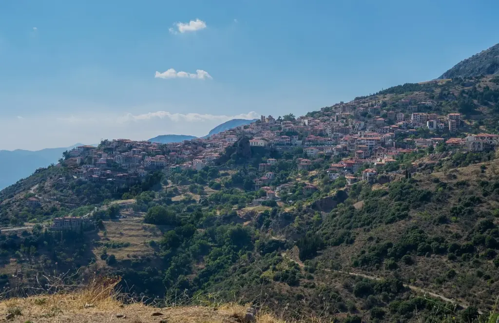 Arachova's houses spread across a green slope of Mount Parnassos under a blue sky
