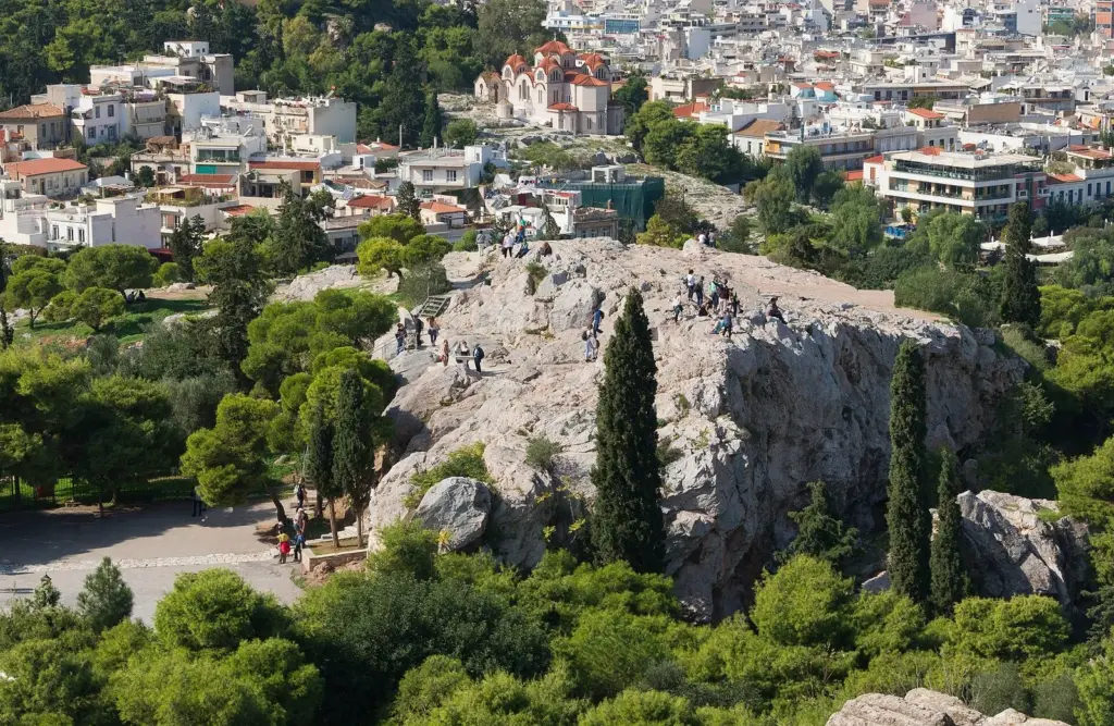People on the bare rock of the Areopagus below the Acropolis, with the city behind