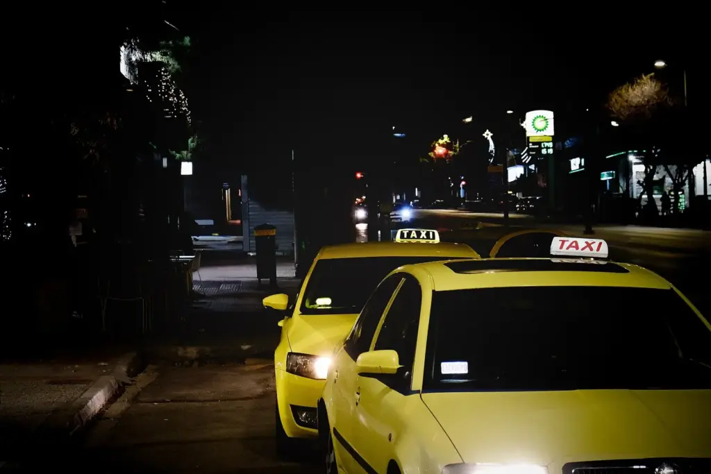 Yellow Athens taxis with illuminated roof signs waiting at a rank at night
