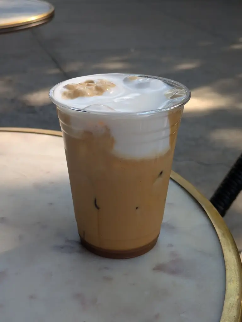 Iced freddo cappuccino in a plastic cup on a round marble café table