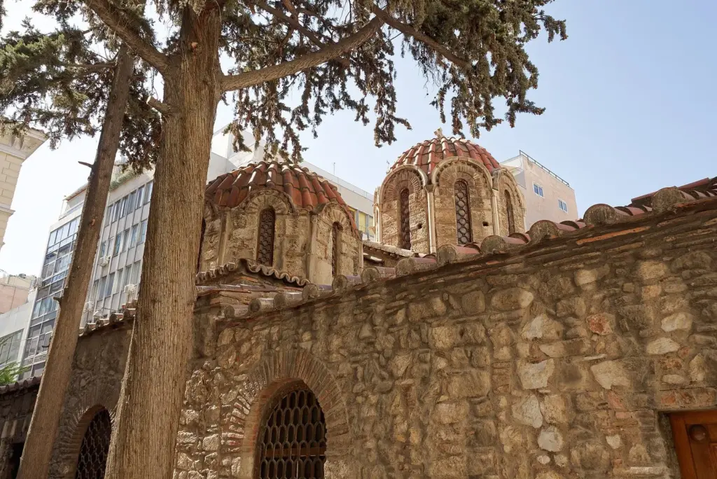 The brick domes of the Byzantine Church of Panagia Kapnikarea behind a pine tree off Ermou Street