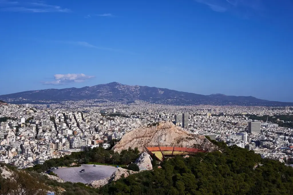 The open-air Lycabettus Theatre set into bare rock on the eastern side of the hill, with the city and mountains beyond