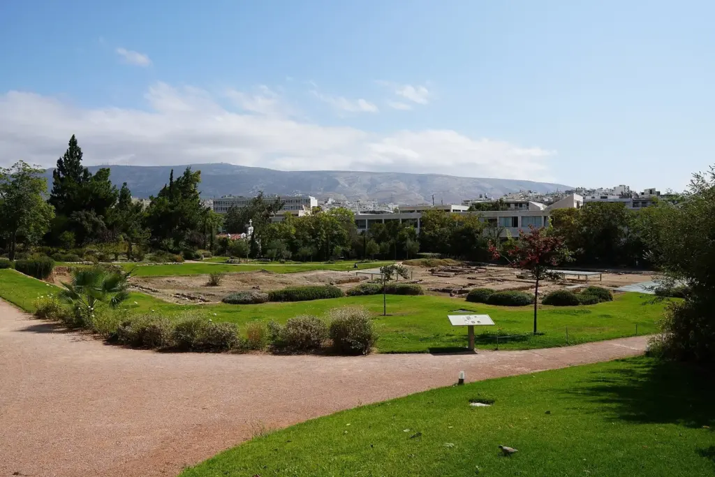 Low excavated foundations of the Lyceum of Aristotle in a garden of grass, shrubs and gravel paths