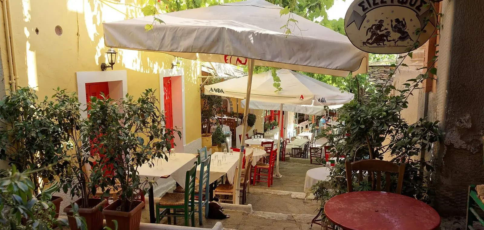 Taverna tables under umbrellas on the stepped Mnisikleous Street in Plaka, Athens