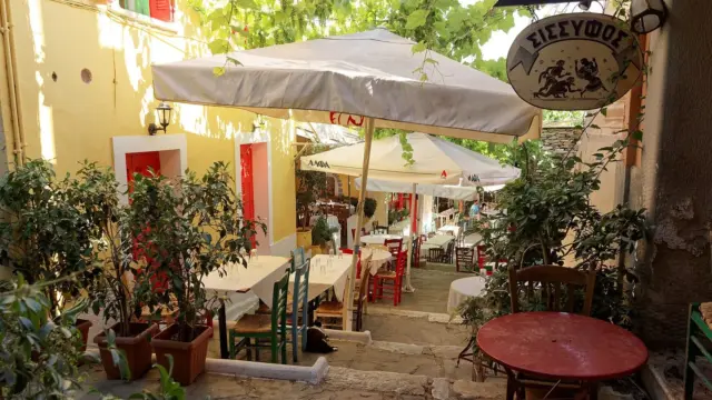 Taverna tables under umbrellas on the stepped Mnisikleous Street in Plaka, Athens