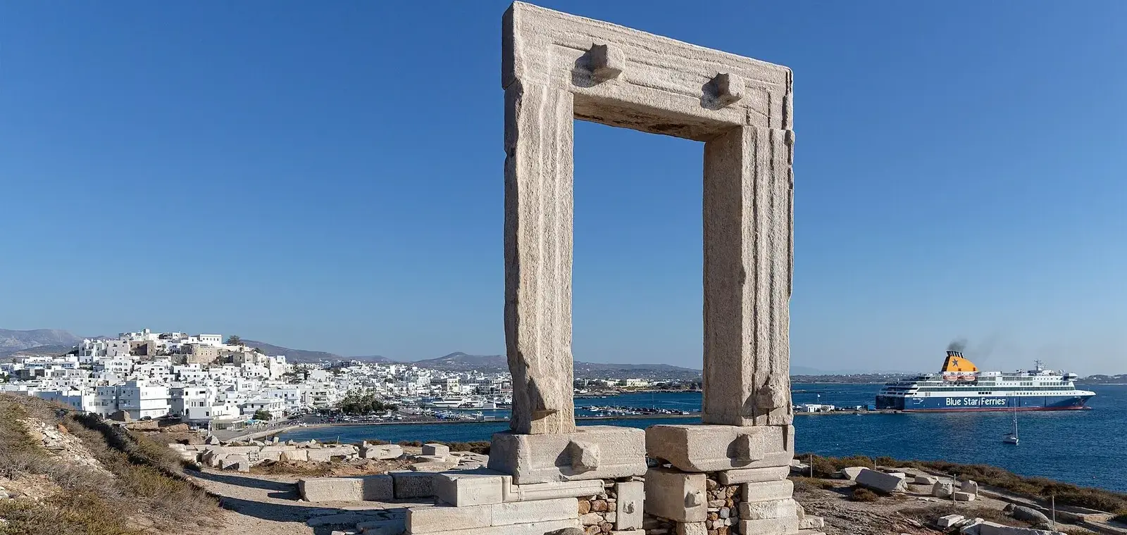 Blue Star ferry heading into Naxos town, seen past the Portara marble gateway