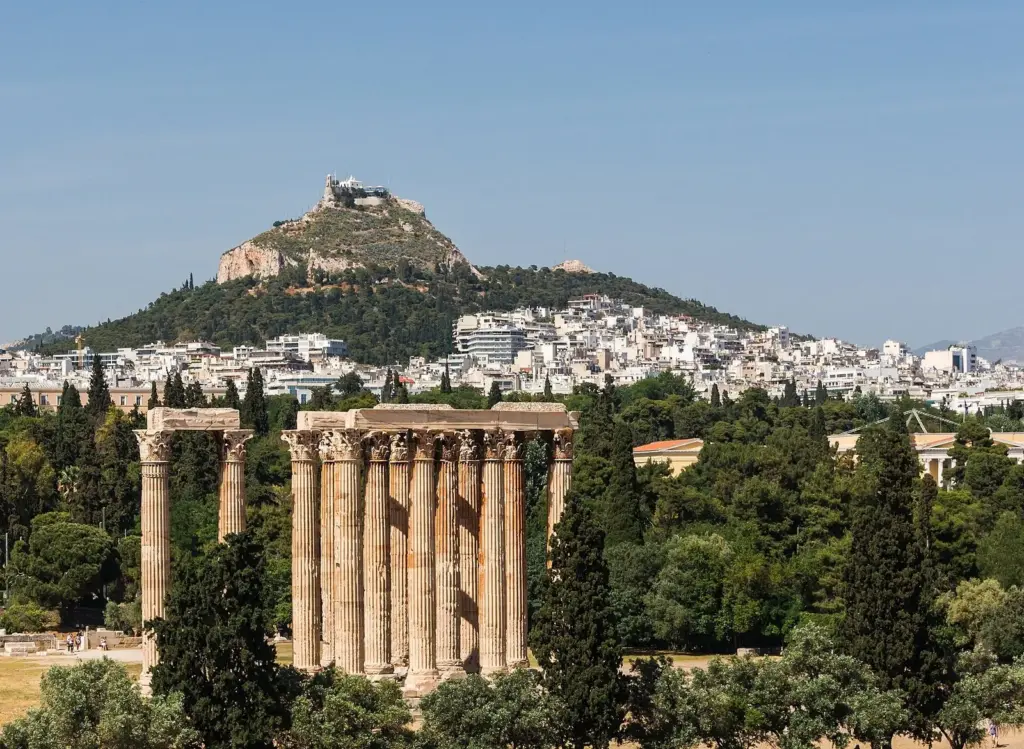 The standing columns of the Temple of Olympian Zeus among trees, with Lycabettus Hill rising behind