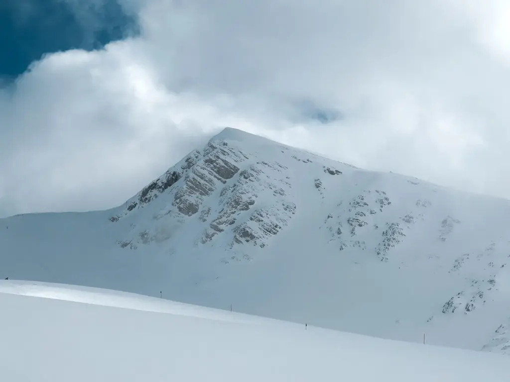 A snow-covered summit on Mount Parnassos with cloud drifting across the ridge