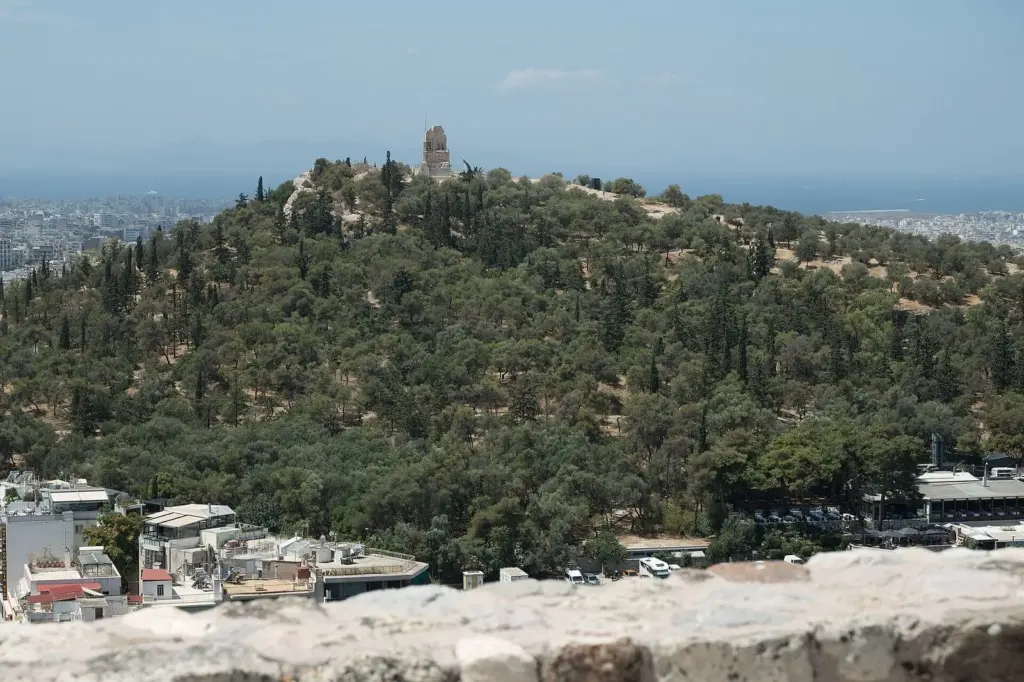 Pine-covered Philopappos Hill with the Philopappos Monument on its summit, seen from the Acropolis