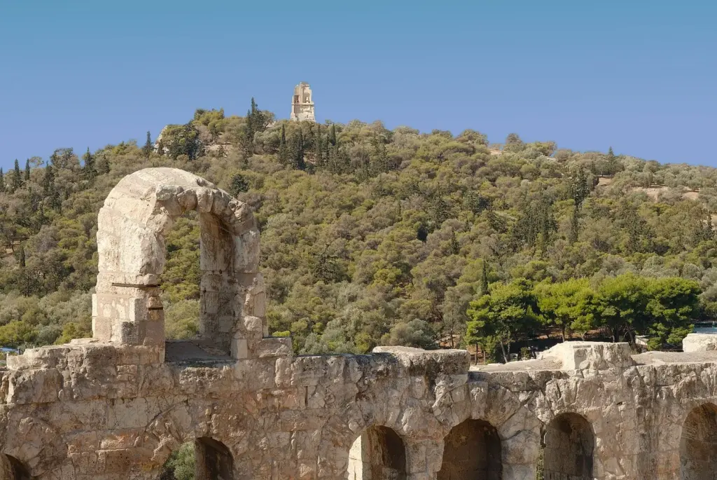 Philopappos Hill and its hilltop monument seen over the arches of the Odeon of Herodes Atticus