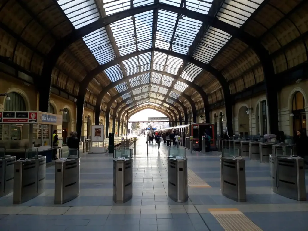 The arched steel and glass hall of Piraeus metro station, with ticket gates in front of the platforms
