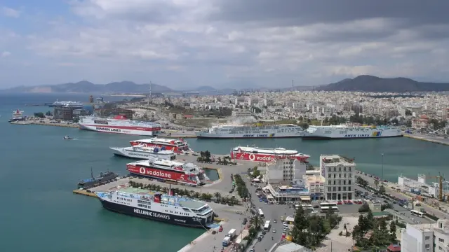 Aerial view of Piraeus port's central harbour, with ferries berthed along the quays and the city and hills behind