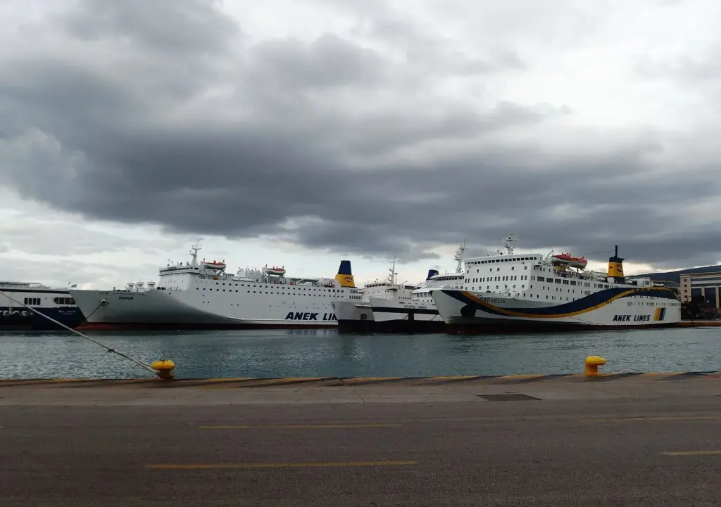 Large passenger ferries moored along the quay at Piraeus under a cloudy sky