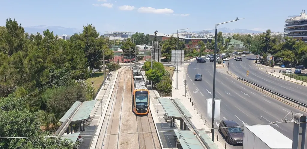 Poseidonos Avenue seen from above, with a tram stop and a tram running beside the carriageway and trees on either side