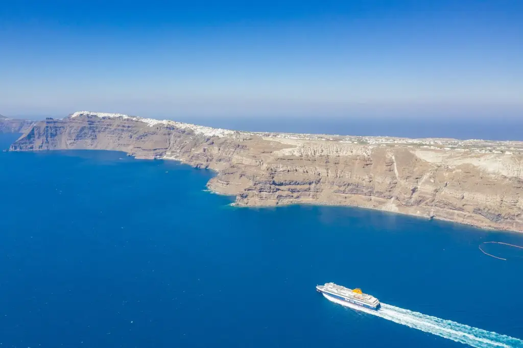 A ferry crossing Santorini's caldera below the cliff-top villages