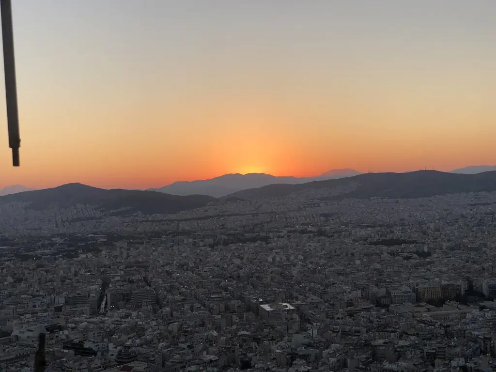 An orange summer sunset behind the mountains west of Athens, seen from the top of Lycabettus