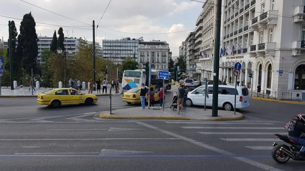 Taxis and a bus at the edge of Syntagma Square, the hub for luggage storage in Athens, with hotels on the right