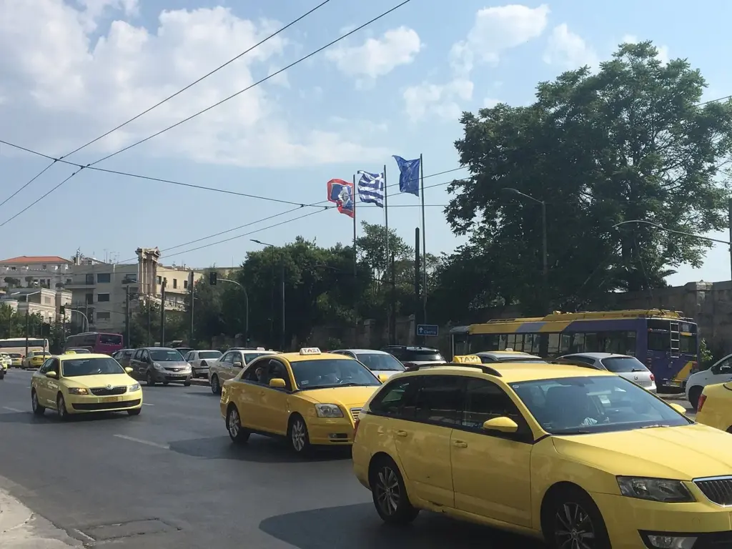 Yellow taxis in traffic on an Athens avenue beside a trolleybus