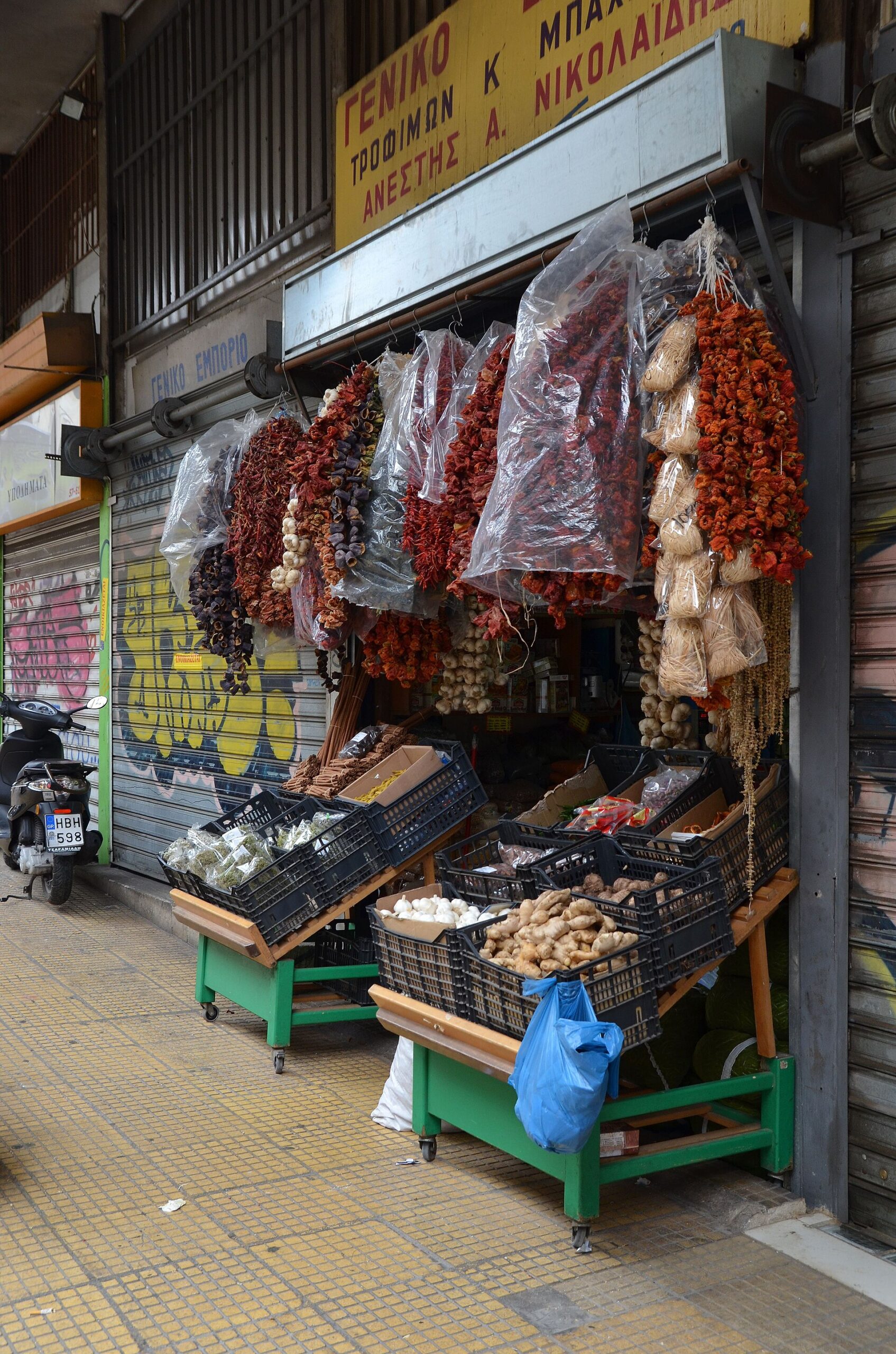 Dried peppers and garlic hang above cinnamon sticks, bagged herbs and ginger outside a spice shop in central Athens.