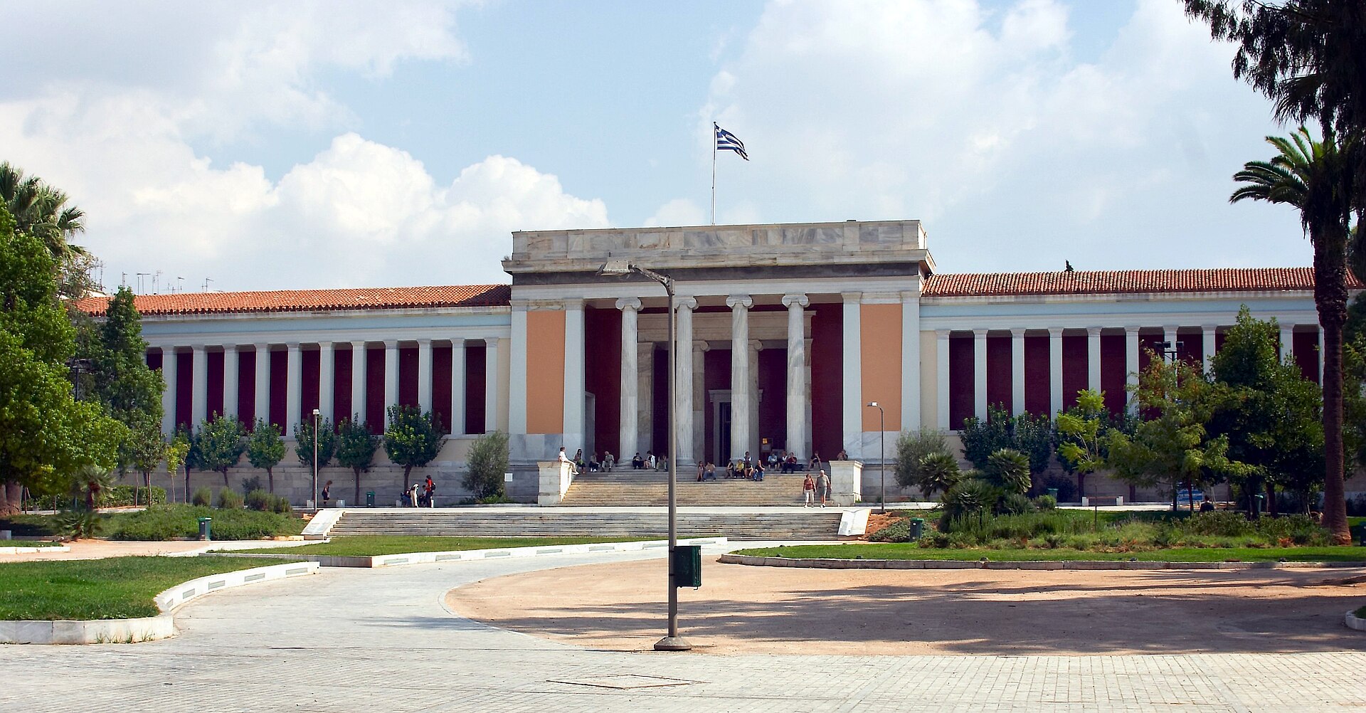 The National Archaeological Museum in Athens displays a central columned portico, red-walled colonnades and broad entrance steps.