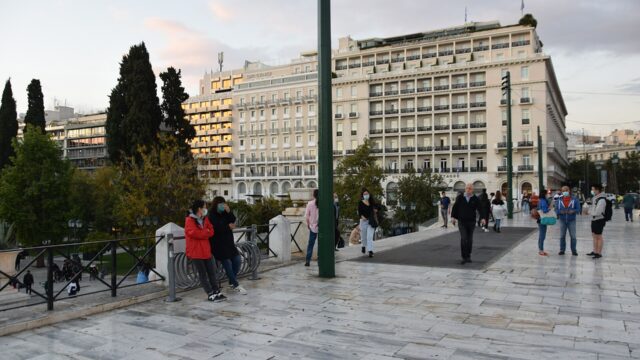 Pedestrians walk across Syntagma Square in Athens in front of the Hotel Grande Bretagne and neighbouring hotel buildings.